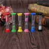 A set of six colorful hourglass sand timers with different durations and colored bases resting on a wooden surface.
