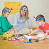 A mother and son are playing a Guess Who I Am card game with family cards on a wooden floor.