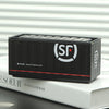 Black miniature industrial iron storage box with a white logo and lid resting on a white book.