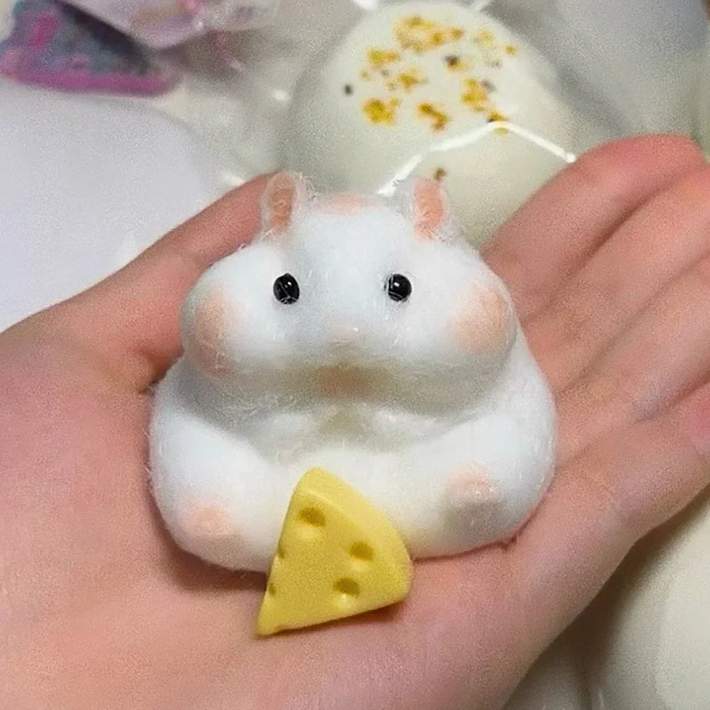 A white silicone hamster fidget toy with pink accents is held in a person's hand.