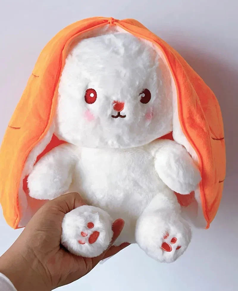 Ein weißer Hasenplüsch mit orangen Ohren und einem Karottenkörper wird von einer Hand gehalten.
