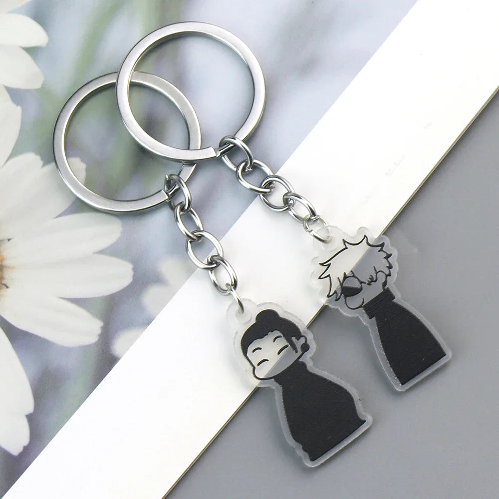 Silver keychain with a black charm featuring an anime-style face and hand print.