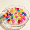 A clear glass bowl filled with 300 pieces of matte stacked translucent beads in various bright colors for jewelry making