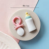 A set of baby-themed silicone cake molds including a yellow bottle, a white bottle, and a pink pacifier.