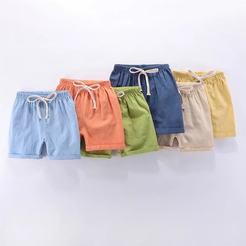 A collection of ten kids summer linen shorts in various colors including blue, orange, green, navy, beige, and yellow.