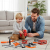 A man is playing with a red electric drill and various orange and gray tools on a carpet.