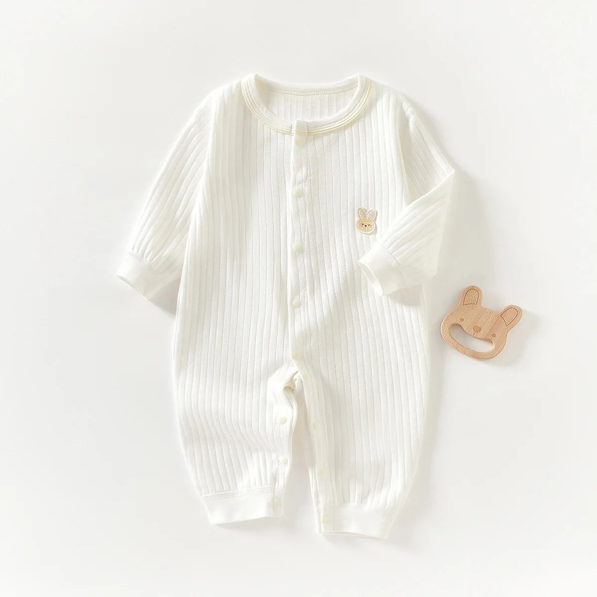 A white ribbed soft cotton baby romper for newborns and infants with a small bear embroidered on the chest.