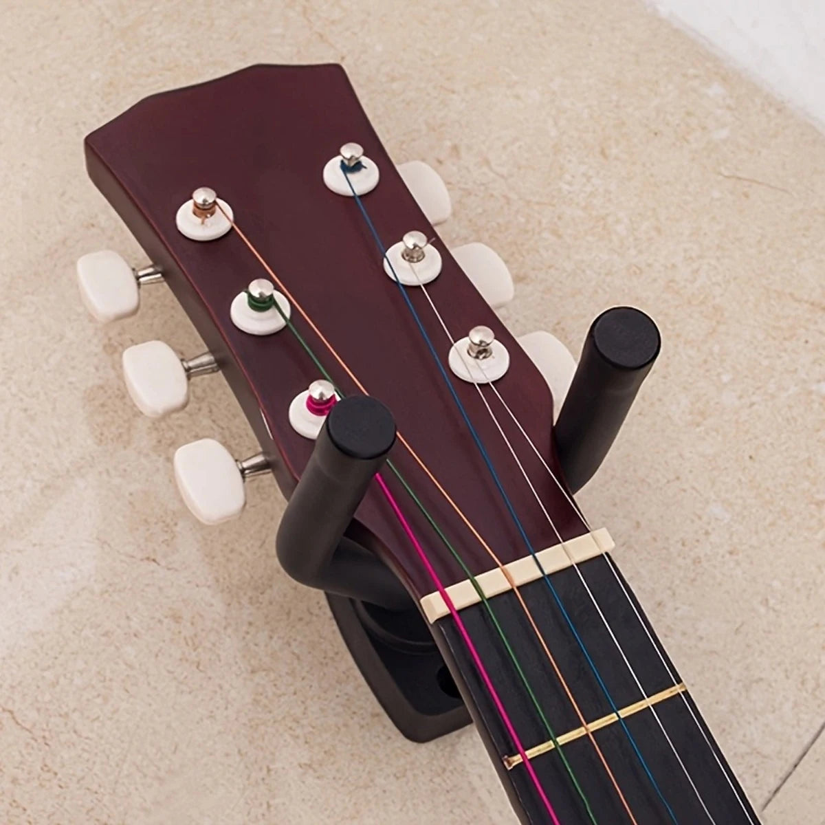 A dark red acoustic guitar is shown mounted on a wall hanger with tuning pegs visible.