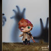 A collectible figure of an orange-haired monster with large eyes standing on a textured surface.