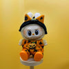 A cute doll wearing an orange and black Halloween pumpkin costume with yellow ears.