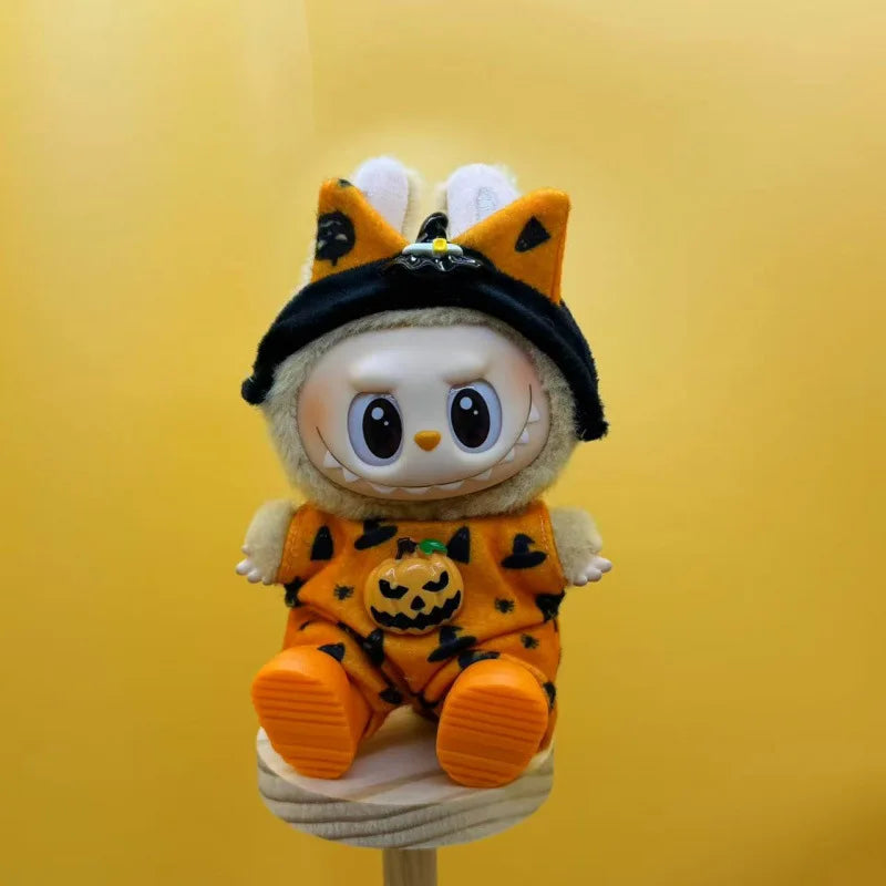 A cute doll wearing an orange and black Halloween pumpkin costume with yellow ears.