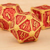 A close-up of a red and gold polyhedral dice set, including a d7, resting on a wooden surface.