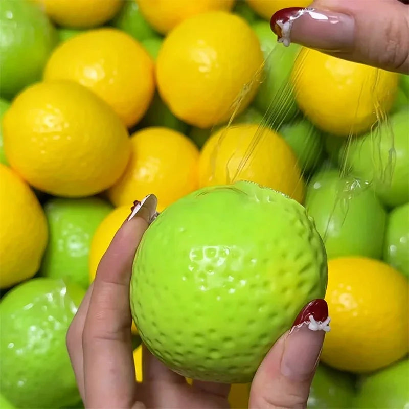 A hand is squeezing a bright green lemon stress ball with a yellow lemon in the background.