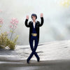 A plush doll resembling Elvis Presley with dark clothing and pink hands standing on a gray surface.