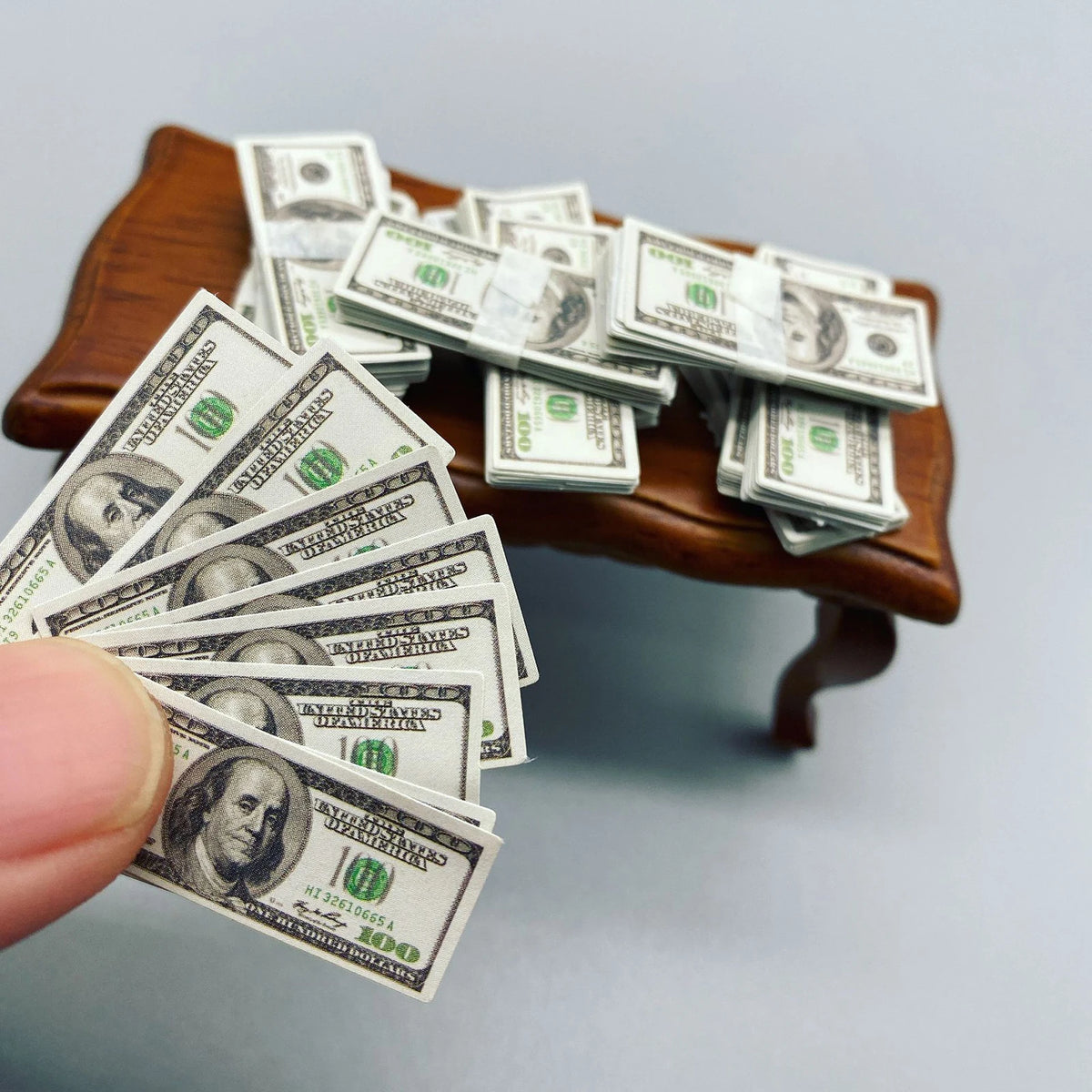 Piles de billets de cent dollars américains posées sur une surface en bois