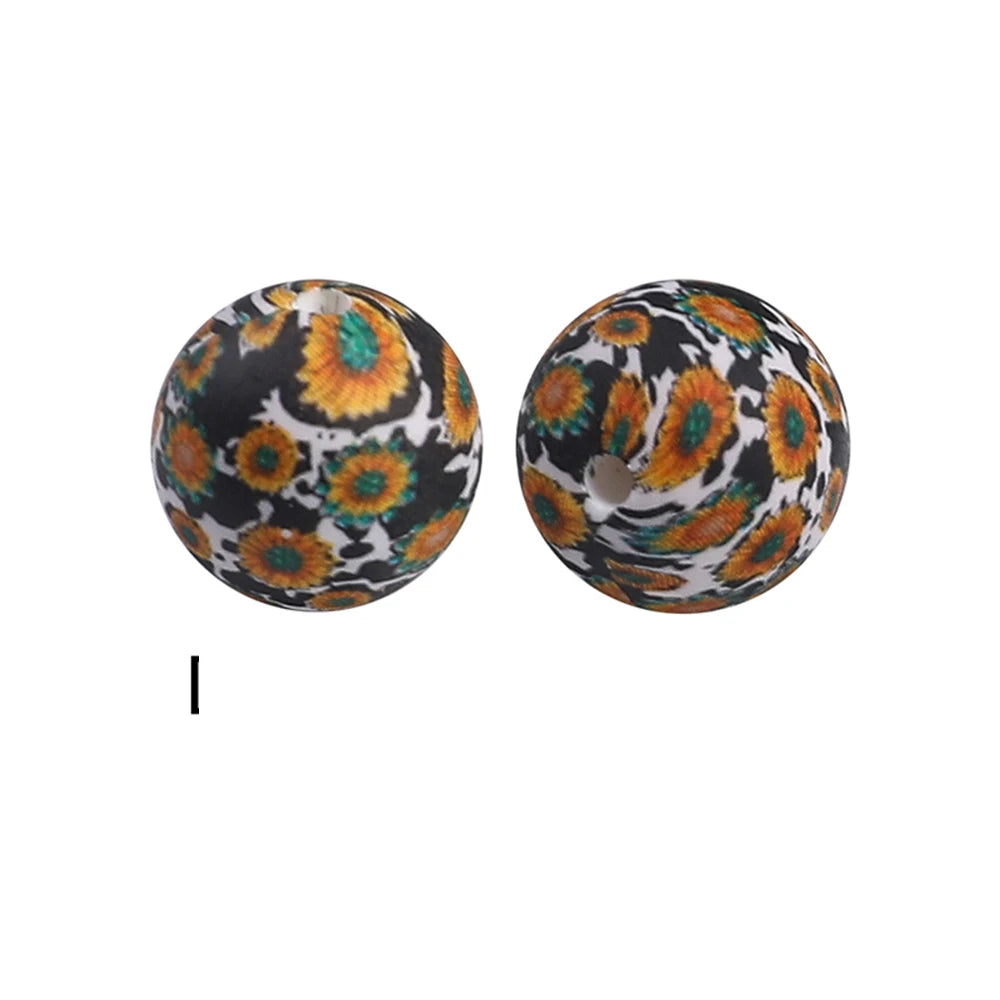 A pair of round, black silicone beads with an orange and yellow floral pattern for jewelry making.