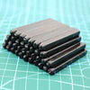 A stack of 36 carbon steel number and letter stamping rods resting on a teal grid surface.