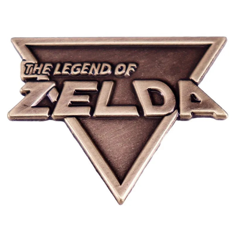 A bronze enamel pin featuring the text The Legend of Zelda in a stylized triangle shape.
