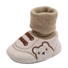 A pair of beige baby soft sole first walker shoes featuring a bear design and knitted cuff.