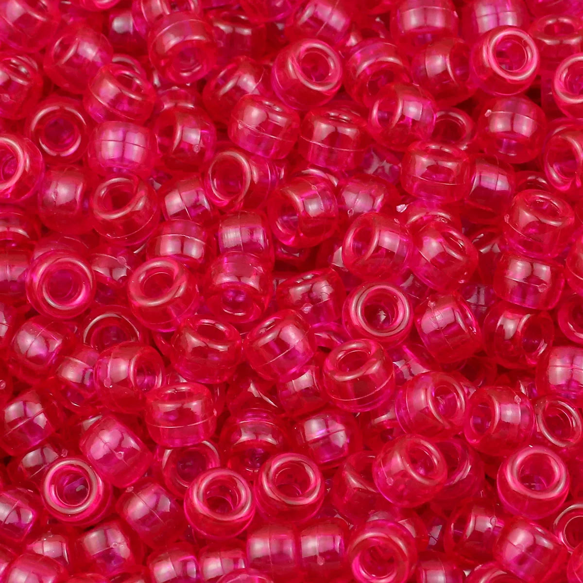 A close-up view of numerous small, translucent pink and red pony beads for jewelry making and crafts.