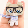 A small, light beige pet figure wearing black glasses and a blue checkered scarf is held in a hand.