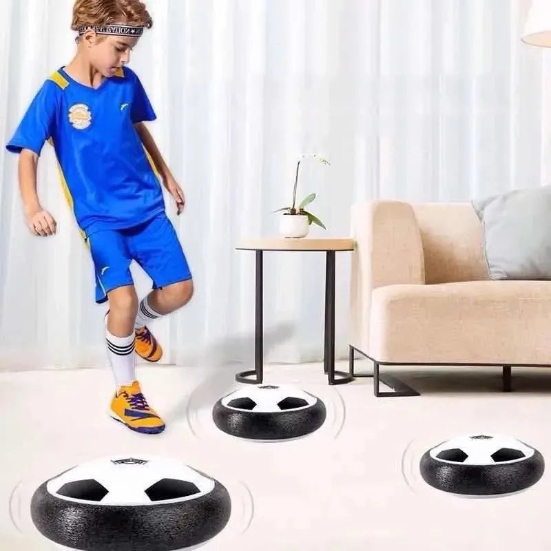 A glowing LED hover soccer ball resting on a white floor with a child nearby.