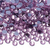 A close-up view of various shades of pink and purple glass crystal rhinestones scattered on a white surface.