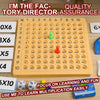 A yellow multiplication chessboard game with numbered squares and colored pieces used for learning.