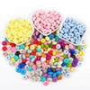 A collection of colorful silicone lentil beads in various shades of pink, blue, yellow, and green are displayed in small bowl