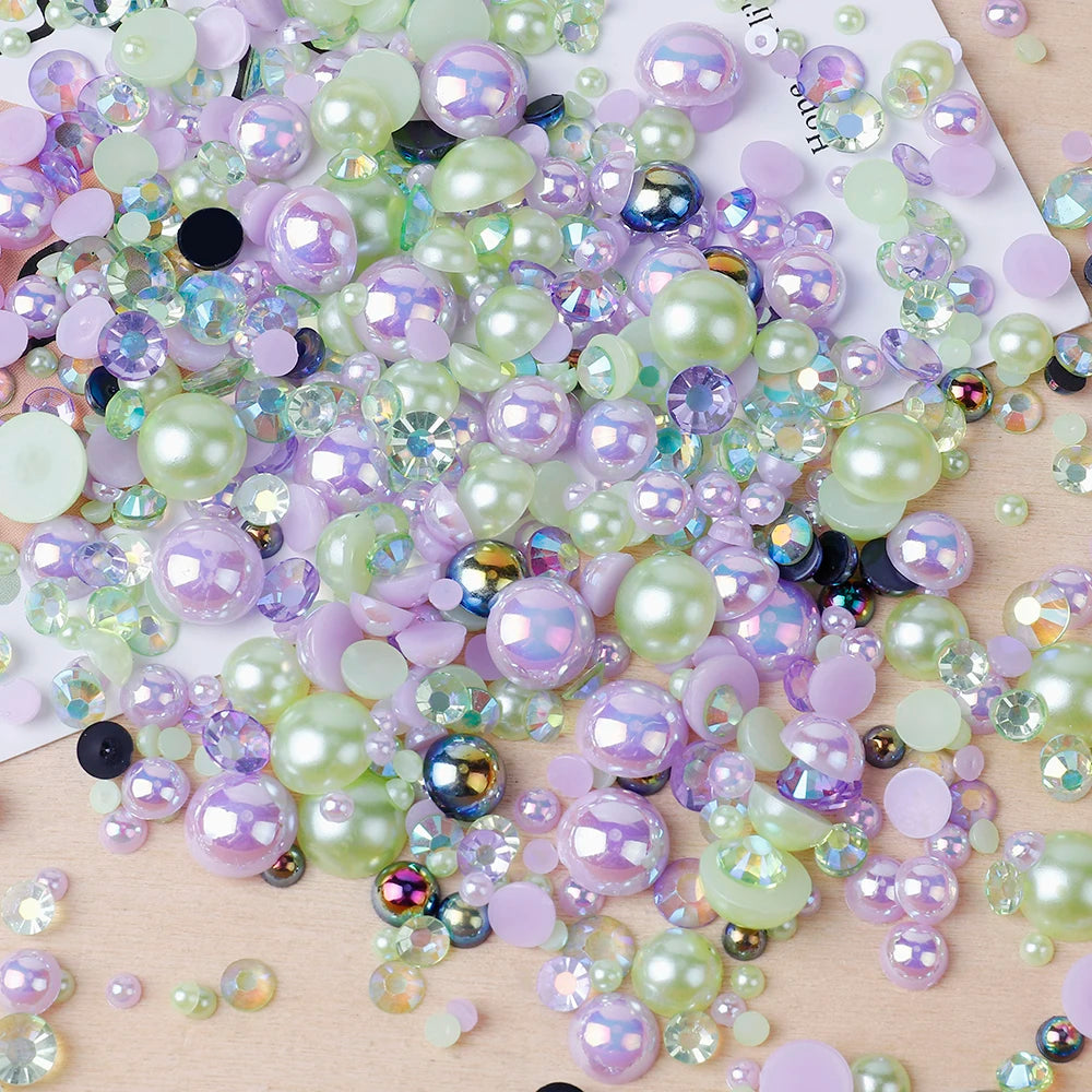 A scatter of mixed resin rhinestone pearls in shades of pink, purple, and green on a light wooden surface.