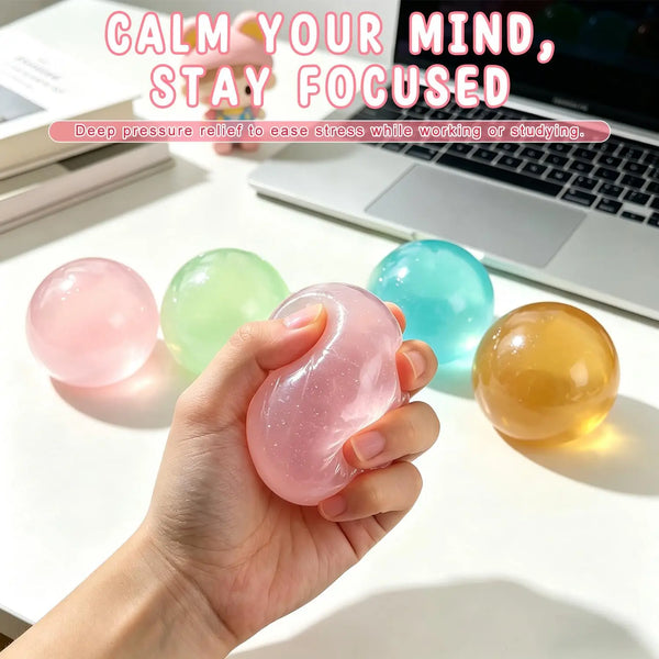 Une main tient une balle anti-stress en huile de coco translucide rose à côté d'un ordinateur portable.