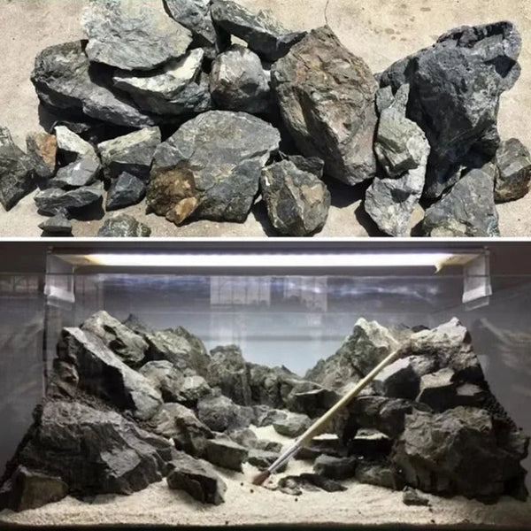 A collection of dark natural stone rocks used as aquarium decor, displayed in a glass tank.