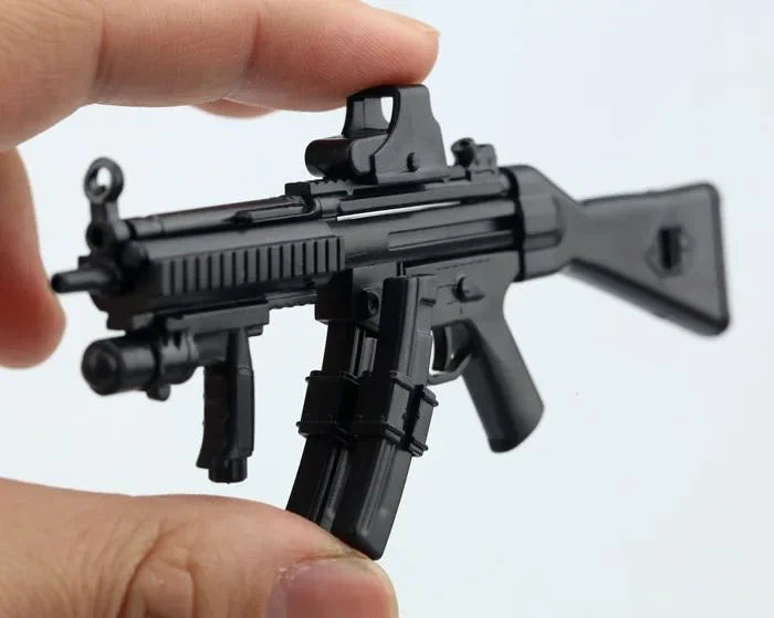 A black 1:6 scale MP5SD5 submachine gun model kit is held by a hand against a white background.