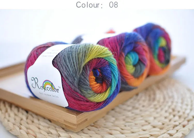 Spool of hand-dyed rainbow merino wool yarn in various vibrant colors resting on a wooden board.