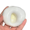 A hand holds a white, squishy sand stress ball with a yellow interior for sensory fidgeting.