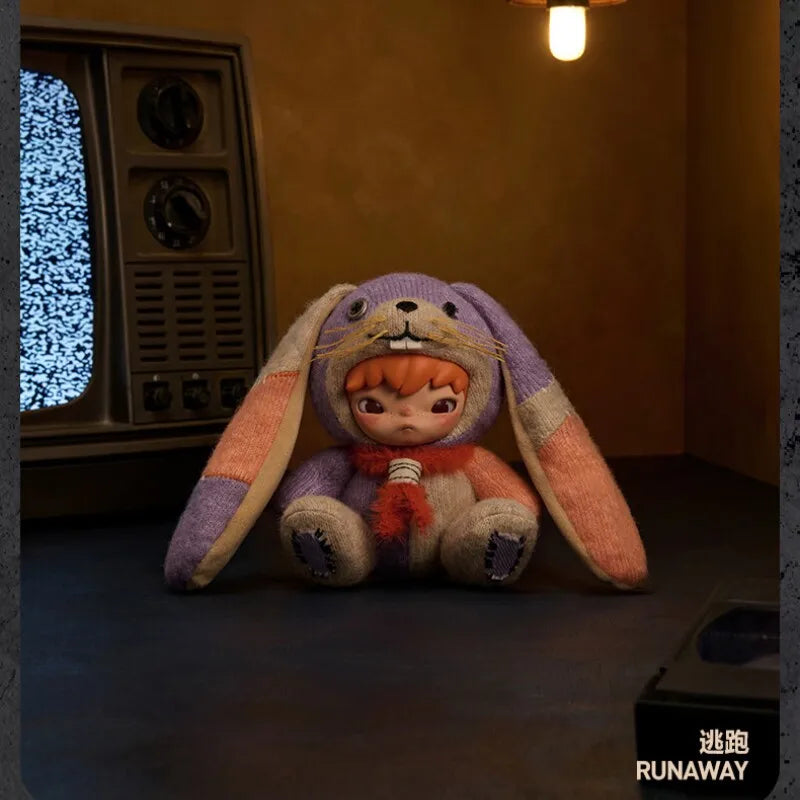 A purple and orange plush doll with long floppy ears sits on a dark surface.