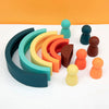 A collection of soft silicone rainbow building blocks in various shades of green, orange, and brown arranged on a white surfa
