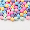 A collection of colorful matte acrylic beads in various shades including pink, purple, yellow, and blue.