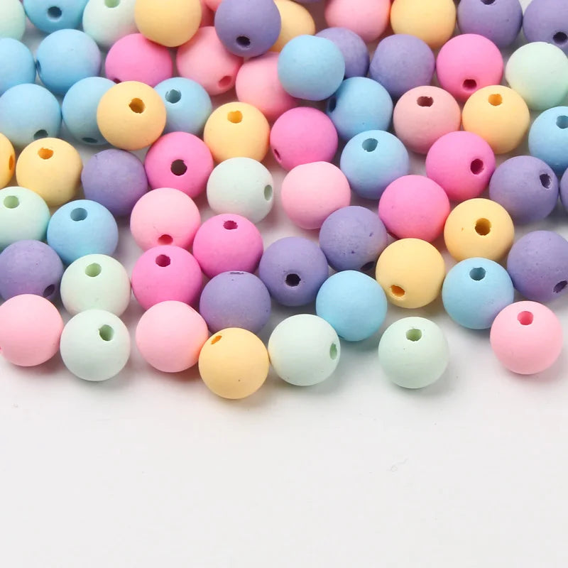 A collection of colorful matte acrylic beads in various shades including pink, purple, yellow, and blue.