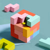 A colorful wooden geometric shape puzzle with pink, orange, green, and yellow pieces arranged in a cube formation.