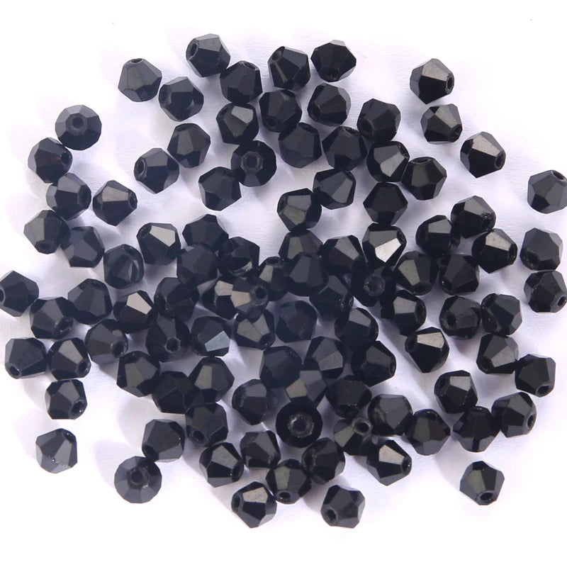 A pile of small, faceted black glass beads shaped like bicones for jewelry making.