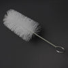 A white trumpet and cornet cleaning kit with piston and mouthpiece brushes lying on a dark surface.
