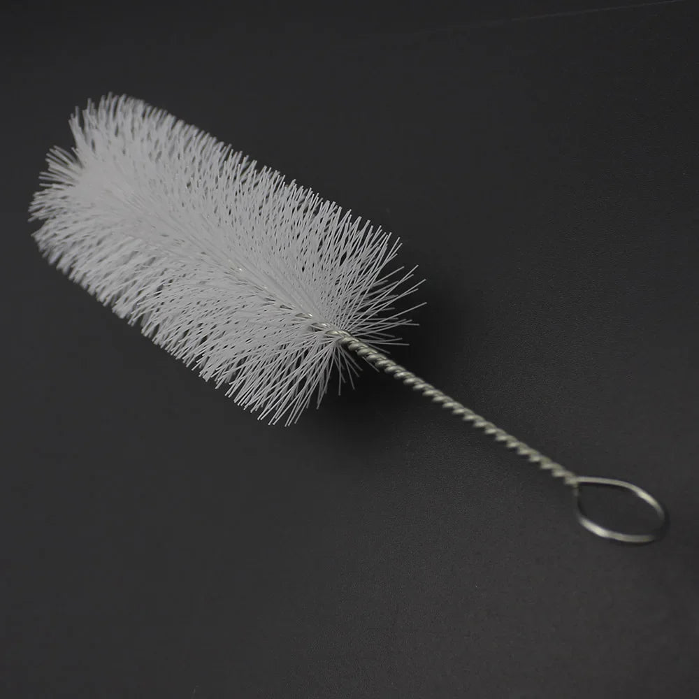 A white trumpet and cornet cleaning kit with piston and mouthpiece brushes lying on a dark surface.