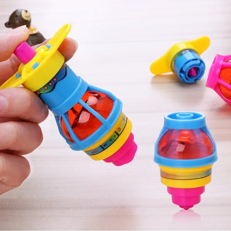 A hand holds a glowing spinning top toy with LED lights, showing various colored components.