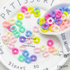 A variety of pastel wavy acrylic beads in pink, yellow, purple, and green are displayed on a white plate.