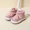 A pair of pink baby winter snow boots with plush lining and white rubber soles resting on a light surface.