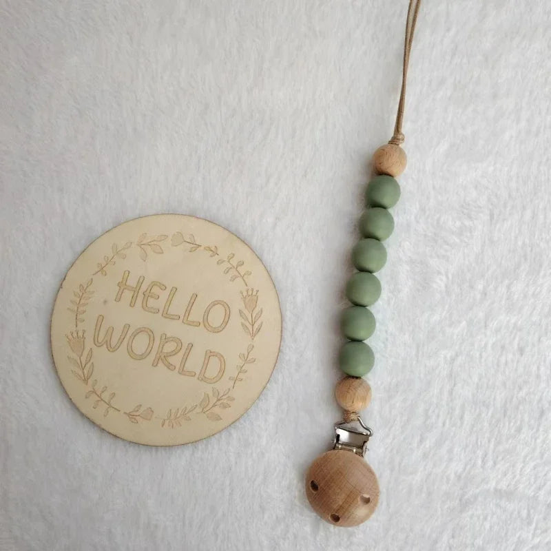 A string of natural wooden beads and a silicone teether attached to a clip on a white background.