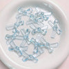 A collection of clear blue acrylic bow tie beads for jewelry making arranged on a white surface.