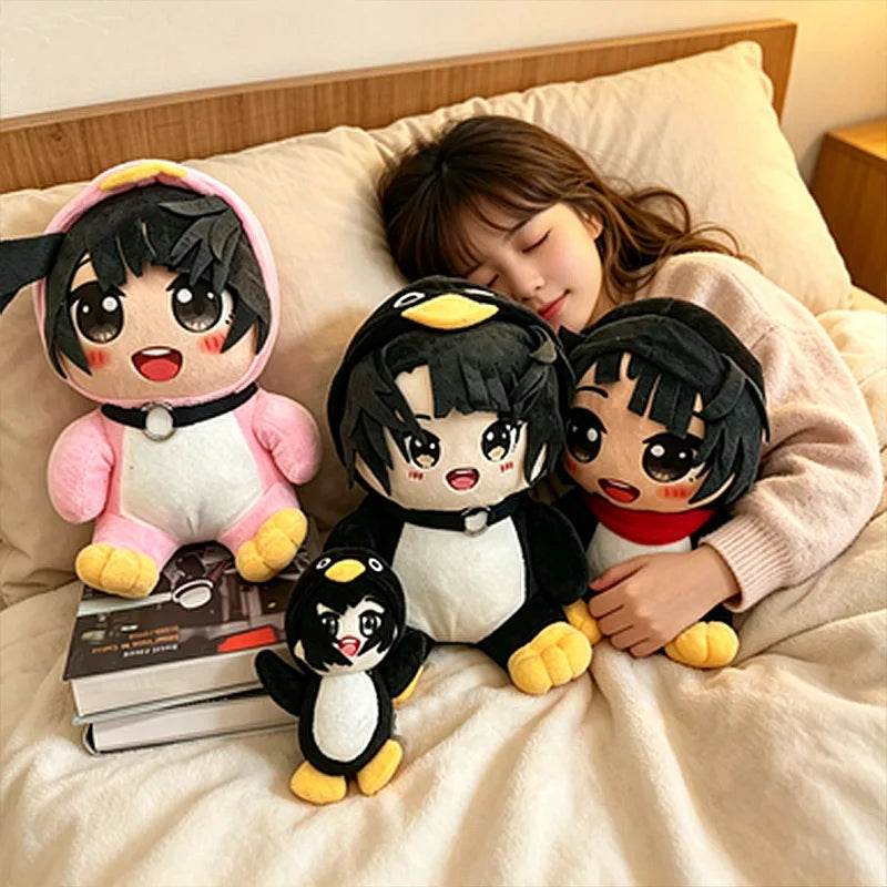 A plush toy featuring a black and white penguin character is resting on a light-colored bed with books nearby.
