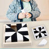 A child holds a white geometric block puzzle piece, with the assembled pieces and an extra piece displayed next to a light be